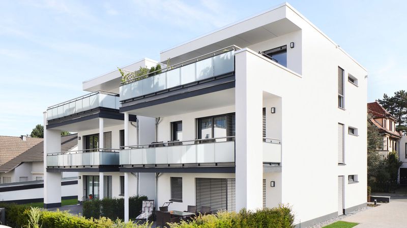 Moderner Neubau eines mehrstöckigen Wohnhauses mit großen Balkonen und Glasgeländern