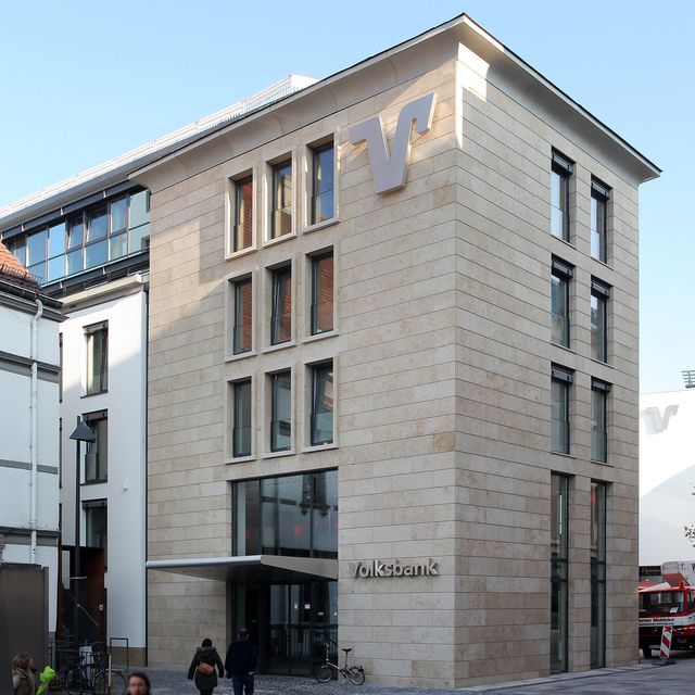 Mehrstöckiges Gebäude mit hellverkleideter Fassade und großem 'Volksbank'-Schriftzug sowie stilisiertem 'V'-Logo an der Ecke